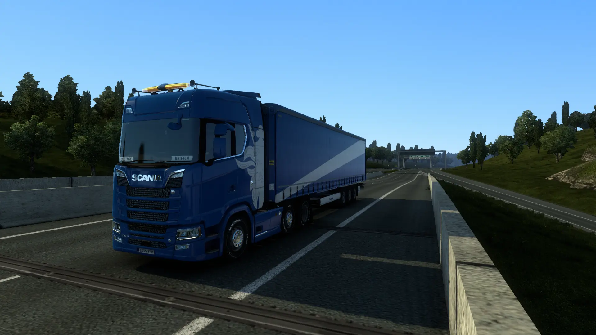 a blue scania truck driving down a highway