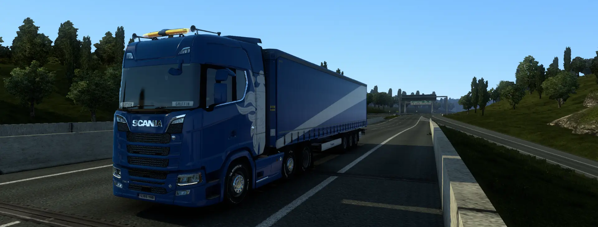 a blue scania truck driving down a highway